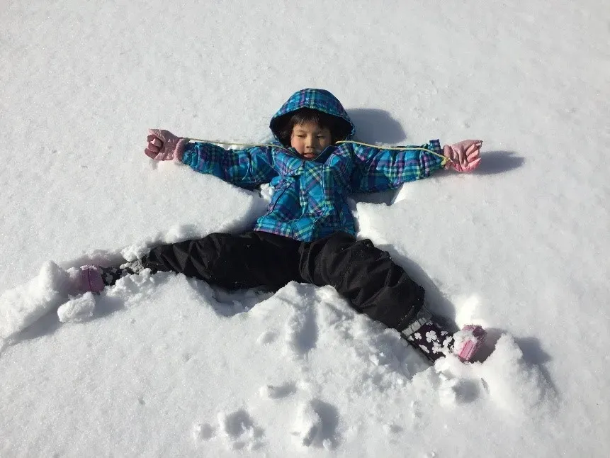 雪の上に大の字で寝転がる子ども