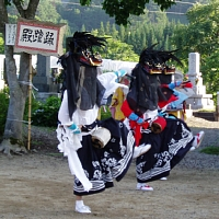 大きな獅子頭をつけ胴幕をたらし、右足を軽く上げるように2人が踊っている写真