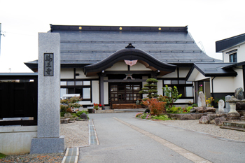 「輪王寺」と書かれた石柱の先に、きれいに剪定された植木や、黒色の屋根をした立派な建物が建っている写真