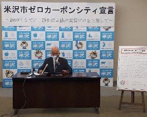 バックパネルの前に座りゼロカーボンシティ宣言を行っている市長の写真
