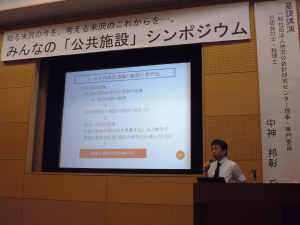 伝国の杜大会議室内の木壁に埋め込まれた巨大モニターを使い、壇上で講演を行う中神 邦彰さんの写真