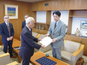 加藤英樹委員長より市長へ意見書を両手で手渡ししている様子の写真