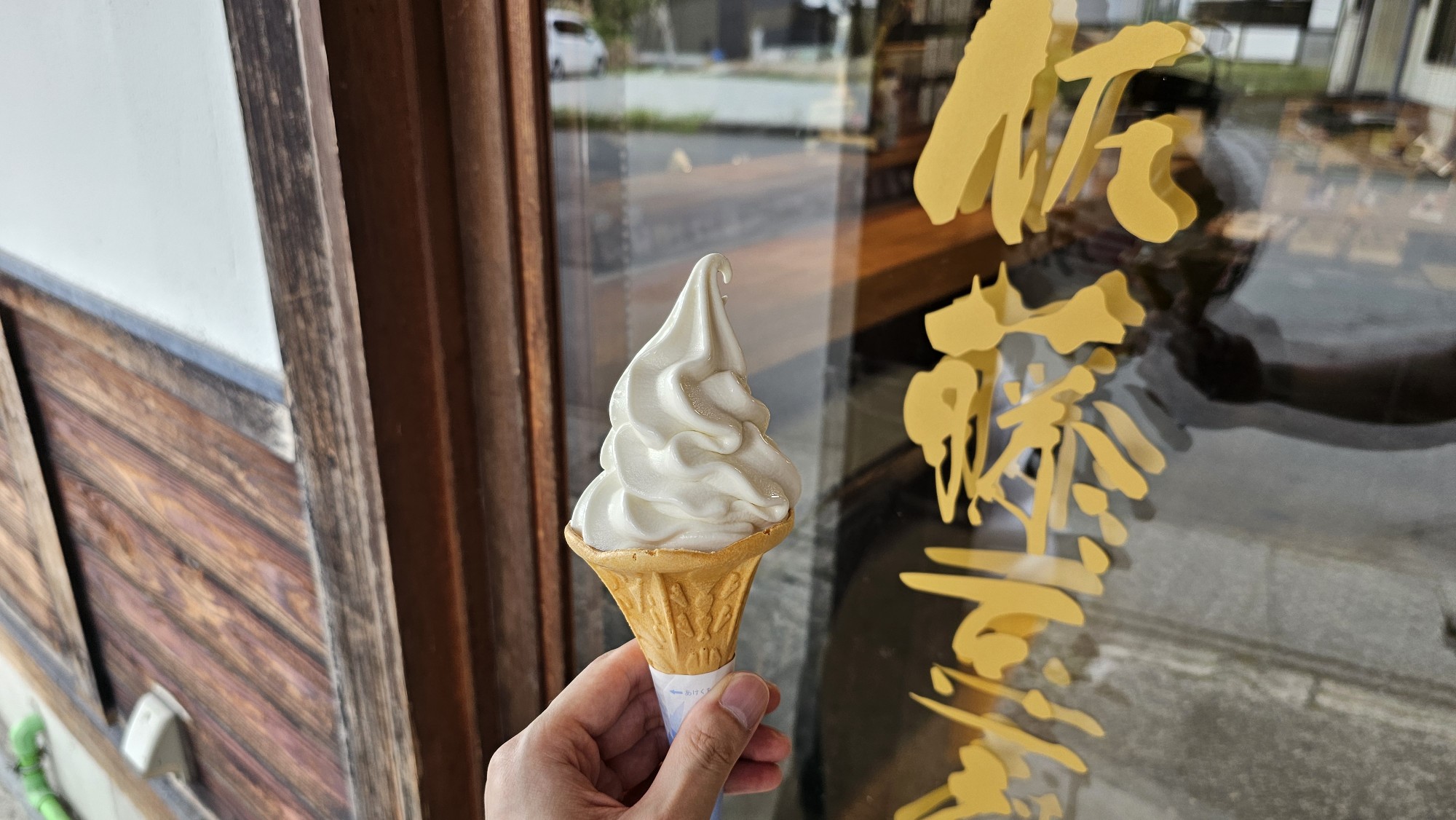 佐藤豆腐屋の前で豆乳ソフトクリームを持っている