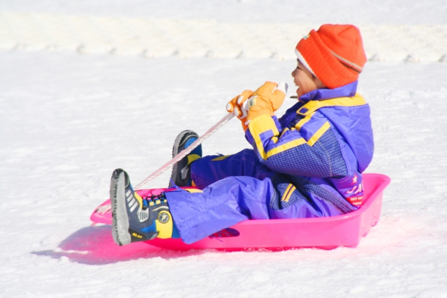 雪上をそりで滑るこどもの画像