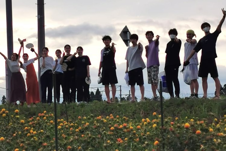 紅花畑でカメラに向かって手を振る若者たち