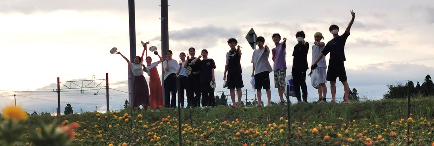 紅花畑でカメラに向かって手を振る若者たち
