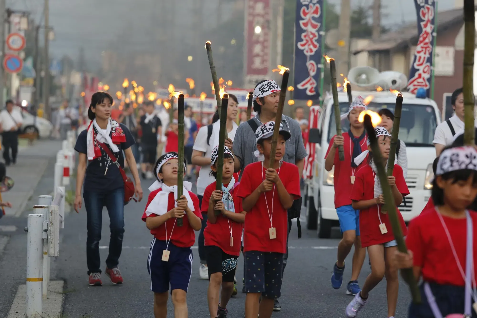 火祭りで灯を掲げて歩くこどもたちの画像