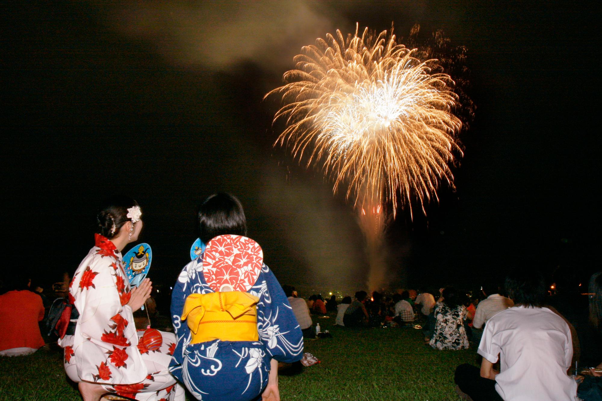打ち上げ花火を見る浴衣の人たちの画像