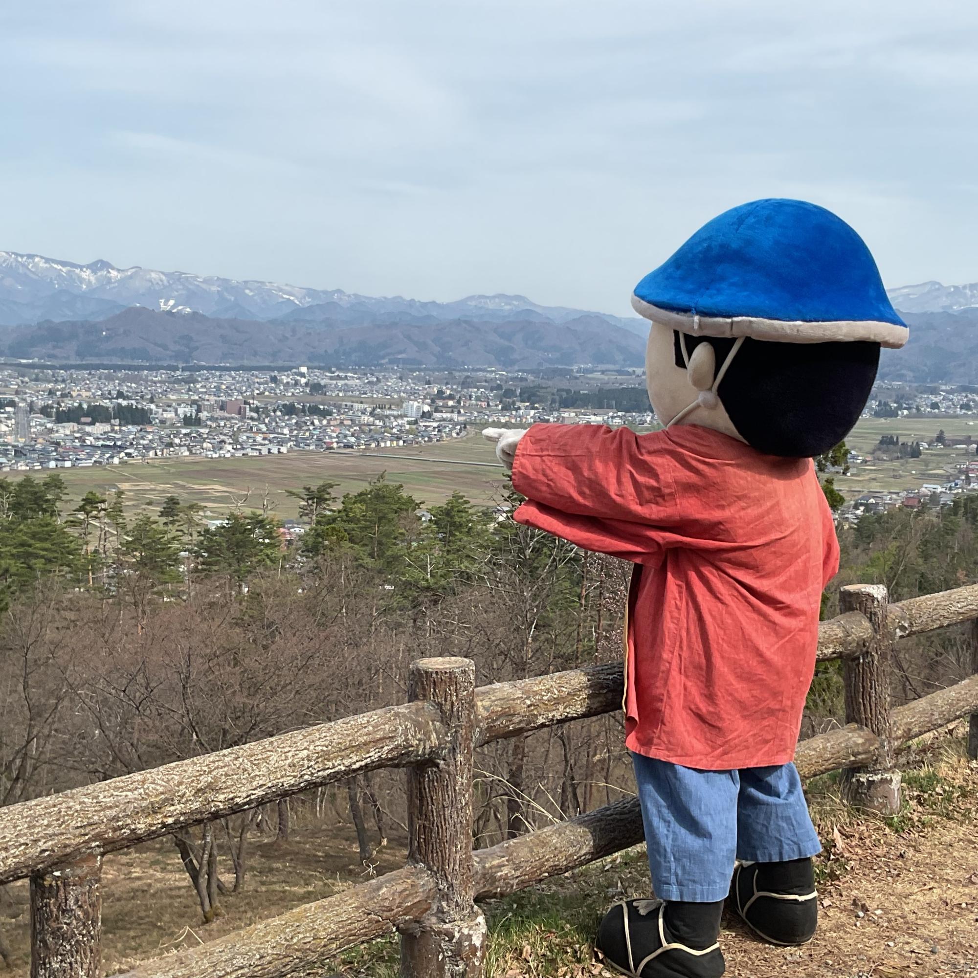 米沢の町並みに向かって指をさすポーズをとるキャラクターの写真