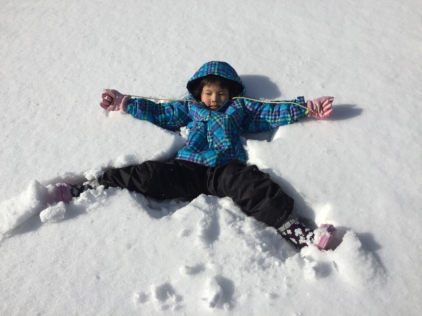 雪の上に大の字で寝転がる子ども
