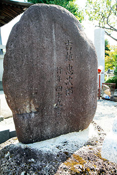 石の上に小判型の石があり、その石の右下に2列で吉雄忠次郎、行年四十九才という文字が彫られた墓石の写真