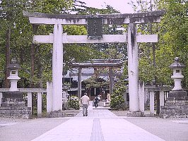 木々に囲まれ中央の鳥居に近い参道には1人歩く男性の後ろ姿があり、その先に次の鳥居が見える上杉神社の写真