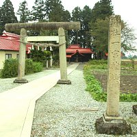 右手前に細長い長方形の石造があり、左側に奥にある「広幡町上小菅一宮神社」へ続くコンクリートで整備された参道とその中間に石造の鳥居がある写真