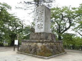 木々に囲まれた中央にある石垣の上にある大きな石碑「招魂碑」の写真