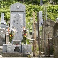 両端に生けた花が飾られ真ん中に文字の彫られている前田慶次の供養塔の写真