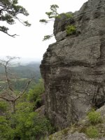 山頂から右手には巨大な岩山、左手には緑の風景が広がっている写真