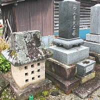 左側に家のような形をした石造のお墓とその右隣に石造りの長方形の山吉家の墓がある写真