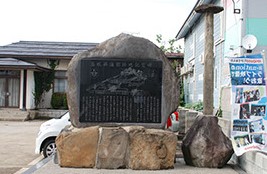 奥に民家が建っており、その前に建てられた記念碑とその右側に「旧藩校興譲館遺蹟」の碑の石柱の写真
