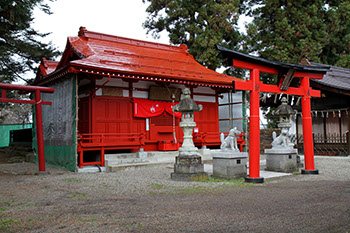 赤い鳥居をくぐり抜けた両脇に狐の狛犬とその後ろに灯篭があり、朱色が特徴的な福徳稲荷神社がある写真