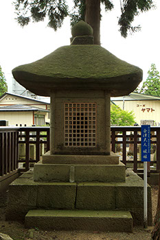 奥にはコーポが並んでおり、その前に「会津夫人媛姫」と書かれた青い札が立っている万年堂づくりの墓の写真