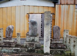 標柱のそばに丸みを帯びた3基の墓石が建てられている写真
