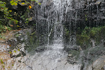 3体ほどの石像に滝の水が落ちてきている様子を撮った写真
