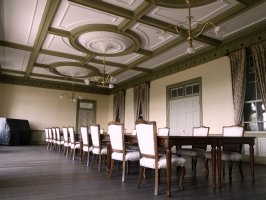 西洋風の机と椅子が並んだ部屋の天井には大きい豪華なシャンデリアが3つ設置されている会議室の写真