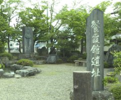 緑の木々があるなか左奥に石碑があり、手前右には餐霞館道遺跡と彫られた石がある鷹山公隠居後の住居跡の写真