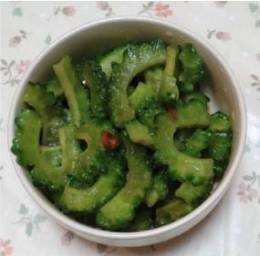 丸い器に盛り付けられた青々とした薄切りされたゴーヤと鷹の爪が入ったゴーヤの醤油漬けの写真