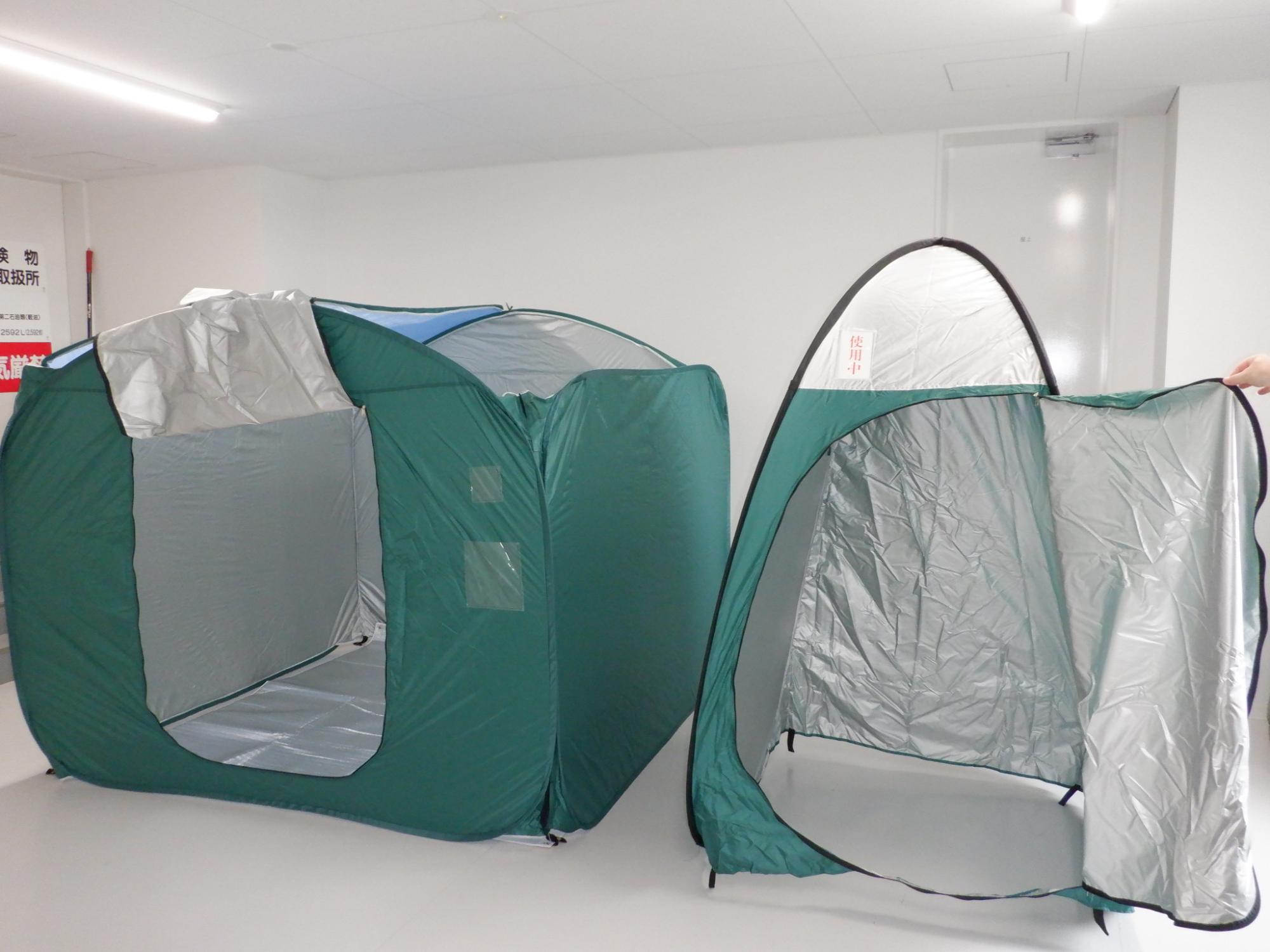 2種類の形で、緑色をしたテントが並べられており、入り口のチャックが開けられ中が見えるように置かれている写真