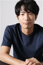 紺のティーシャツを着て手前で手を組み、黒髪の爽やかに微笑む男性眞島秀和さんの写真