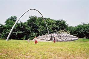 芝生の広がる公園にソッリーゾのモニュメントが設置され、周りを子どもたちが走っている様子の写真