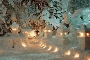 中央に設けられた歩道の両側に、やさしい灯りがともる雪で作られた6基の雪灯篭と、奥の方には枝に雪が降り積もっている木々の写真