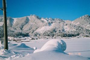 真っ青な青空の下、背景に愛宕山を望み、一面真っ白な雪が降り積もっている様子の写真