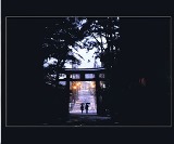 大きな鳥居の下に2名の人が並んでいる様子がシルエットになっている写真