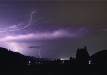 厚い雲が覆う夜空を、いくつもの稲光が走っている様子の写真