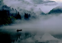 湖面に、深い霧が立ち込めた山並みがきれいに反射している写真