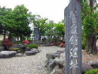 手前に餐霞館遺址と書かれた看板があり、奥に日本庭園が広がる景観写真