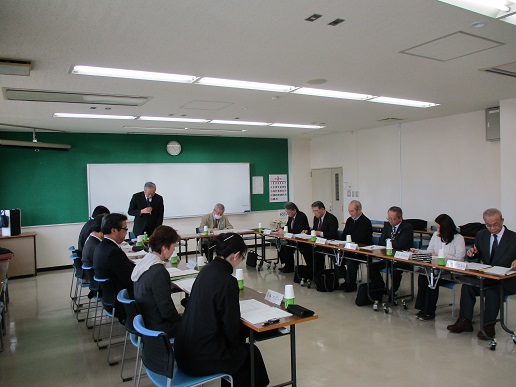 コの字型に長机とパイプ椅子が設置され、参加者が集まり懇談会が行われている様子の写真