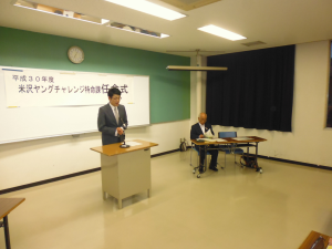 会場の演台の前に立って話をしている様子の米沢まちの駅運営協議会佐藤会長の写真