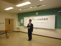 正面に「米沢ヤングチャレンジ特命課任命式」と書かれた紙が設置された会場で、背筋を伸ばした1名の男性が挨拶をしている様子の写真